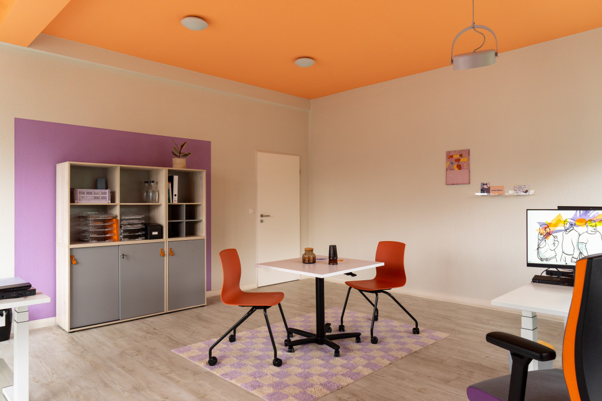 Büroraum mit Besprechungstisch und orangener Decke