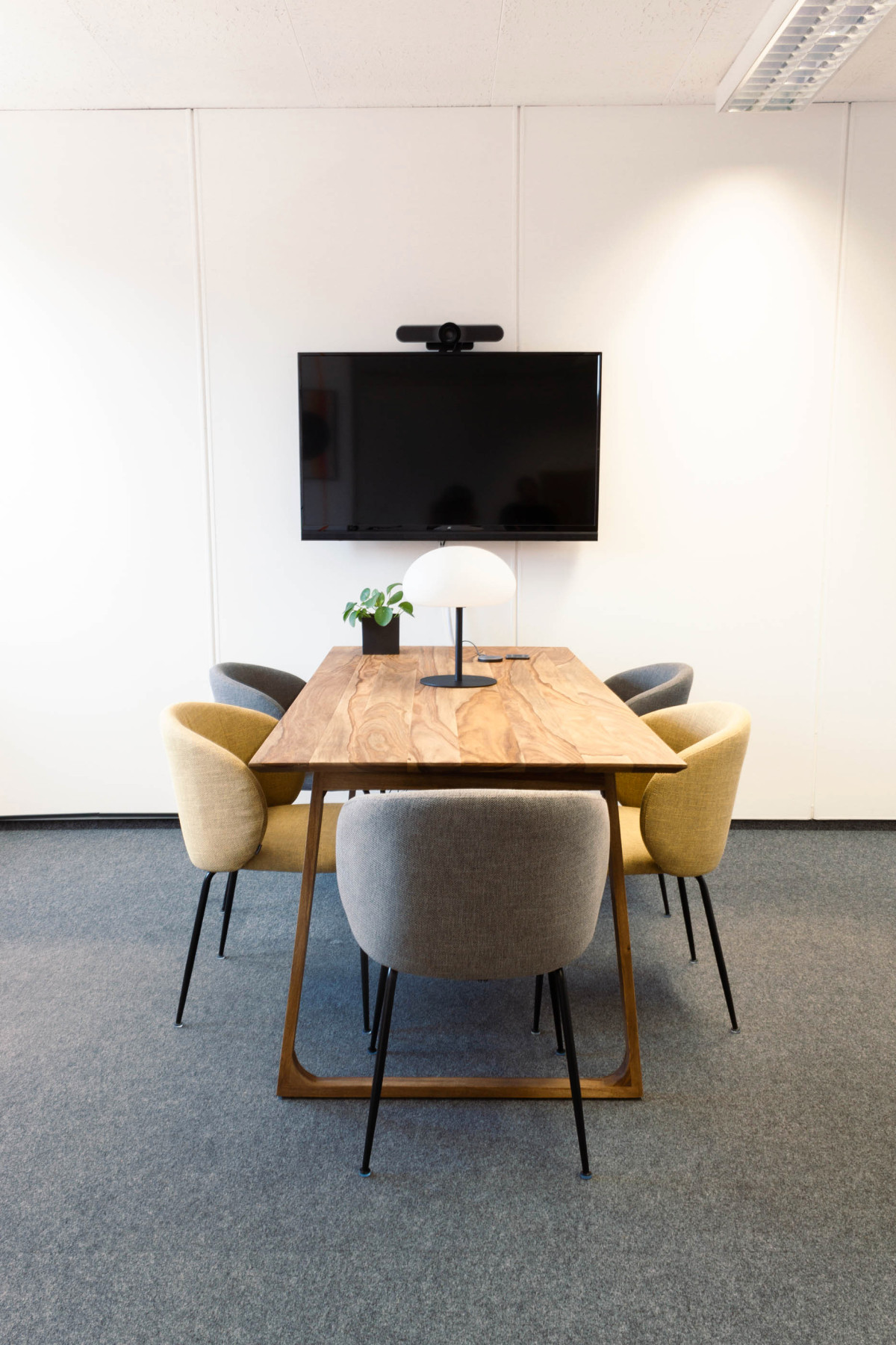 Großer Meeting-Tisch mit farbigen Stühlen und Monitor